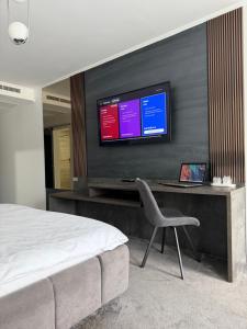 a bedroom with a desk with a television on a wall at Elbram House in Dubova