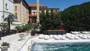 eine Terrasse mit Stühlen und ein Swimmingpool in der Unterkunft Hotel Ostrov in Călimăneşti