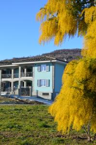 an apartment building with a yellow tree in the foreground at Casa Piutin, appartamento Bucaneve in Bagnolo Piemonte