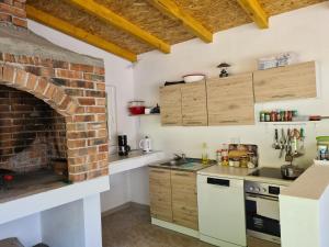 a kitchen with a brick fireplace and white cabinets at Apartman Sunce in Jerkovići