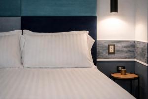 a bedroom with a bed with white pillows and a table at Hotiday Napoli Maradona in Naples