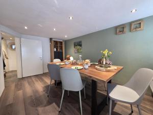 a dining room with a wooden table and white chairs at Der kleine Eifel-Ritter in Manderscheid