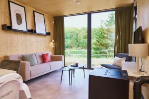 a living room with a couch and a large window at UplandParcs Sauerland in Winterberg