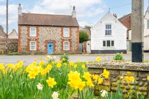 a house with yellow flowers in front of a street at Mill House Cottage in Brancaster