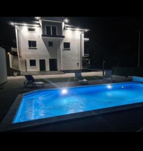 a large blue swimming pool in front of a building at Apartman Sunce in Jerkovići