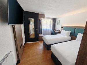 a hotel room with two beds and a mirror at The Crossway Hotel, Coventry Walsgrave, Part of AG Collection in Coventry