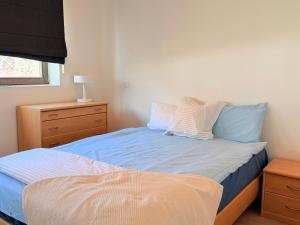 a bedroom with a bed with blue sheets and a dresser at Camelia 0202 - With Swimming Pool in Koksijde