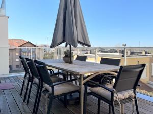 a wooden table with chairs and an umbrella on a balcony at Camelia 0202 - With Swimming Pool in Koksijde