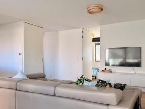 a white living room with a couch and a flat screen tv at Camelia 0202 - With Swimming Pool in Koksijde