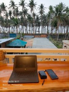 a laptop and a cell phone on a wooden table at Farmhouse With Ocean View in Bolinao