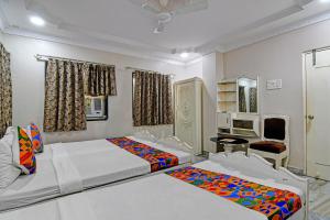 a bedroom with two beds and a chair in it at FabHotel Wellesley in Kolkata