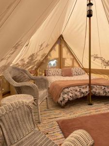 a bedroom with a tent with a bed and chairs at The Apple Farm Glamping in Snitterfield
