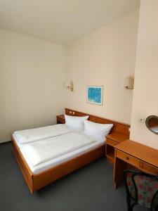 a bedroom with a large bed and a desk at Hotel Drei Rosen in Borna