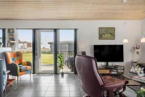 a living room with a flat screen tv and chairs at LF10202-Thyholm-Markvejen-2 in Thyholm