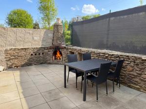 a patio with a table and chairs and a brick fireplace at Chalet U Pstruha in Vimperk