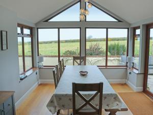 a dining room with a table and some windows at Cefn Y Gwynt in Llangranog