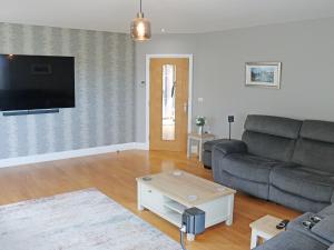 a living room with a couch and a flat screen tv at Cefn Y Gwynt in Llangranog