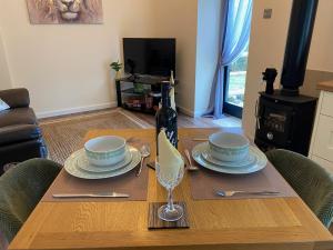 a table with plates and a bottle of wine on it at Serenity- Uk38551 in Endon