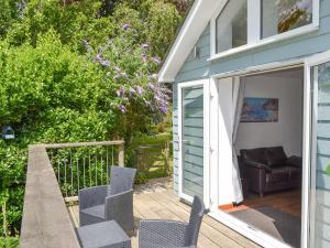 een terras met stoelen en een bank op een veranda bij Sunset in St Austell