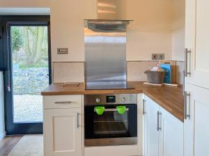 a kitchen with a stove top oven with two green mugs at Serenity- Uk38551 in Endon +30 photos
