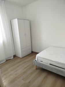 a white bedroom with a bed and a cabinet at Light Loft Marsciano in Marsciano
