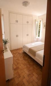 a bedroom with a bed with white cabinets and a wooden floor at Capo d'Arco Residence Bilocale tra Mare e Natura in Capo D'Arco +21 photos