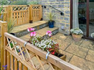 a wooden fence with flowers on a patio at Chapel Barn - Uk46738 in Shapwick