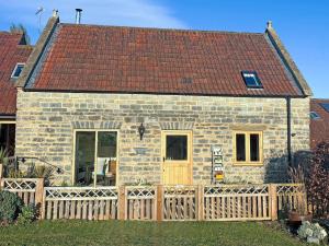 a brick house with a wooden fence in front of it at Chapel Barn - Uk46738 in Shapwick