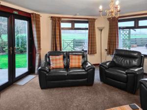 a living room with a leather couch and a chair at Trebor Cottage in Annan +19 photos