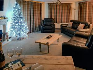a living room with a christmas tree and a table at Trebor Cottage in Annan