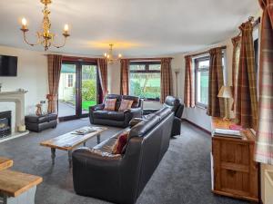 a living room with leather furniture and a fireplace at Trebor Cottage in Annan