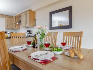 a dining room table with glasses of wine and flowers at 6 Harbour View in Newquay