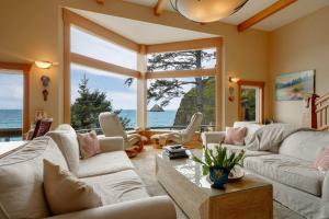 a living room with white furniture and a large window at Ocean's Edge in Tillamook