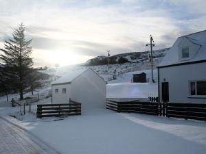 a snow covered field with a house and a barn at Lephin Cottage in Glendale