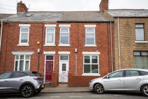 two cars parked in front of a brick house at Vacant Nests The Ropery 4BR Seafront in Seaham