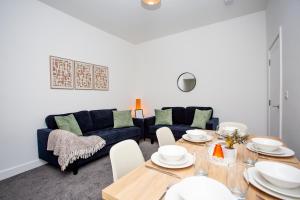 a living room with a blue couch and a table at Vacant Nests The Ropery 4BR Seafront in Seaham