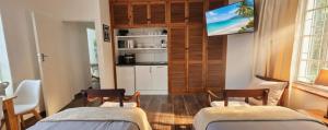 two beds in a room with a tv on the wall at Rus en Vrede BackPackers Cottage! in Knysna