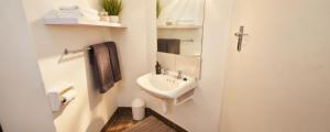 a white bathroom with a sink and a mirror at Rus en Vrede BackPackers Cottage! in Knysna