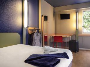 a room with two beds and a table and chairs at ibis budget Arles Sud Fourchon in Arles