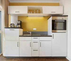 a kitchen with white cabinets and a sink at Central Suites in Greifswald