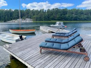 a group of blue chairs sitting on a dock on a lake at Stunning Waterfront Property in the Outer Archipelago in Kyrkkobben