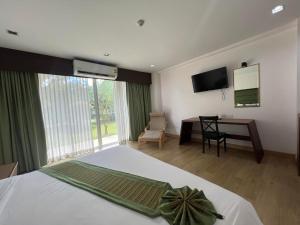 a bedroom with a bed and a desk and a television at Teak Garden Resort, Chiang Rai in Chiang Rai
