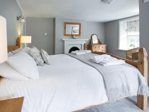 a bedroom with a large white bed and a fireplace at Hudson Cottage - Uk38152 in Newton +6 photos