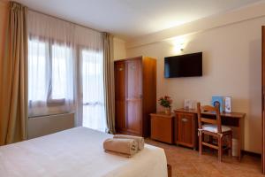 a bedroom with a bed and a desk and a television at iH Hotels Le Zagare Resort in Villasimius