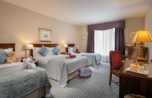 a hotel room with two beds and a chair at Abbey Hotel Roscommon in Roscommon