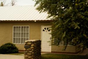 a house with a white door and a stack of logs at Hotel de Campo Calingasta in Calingasta