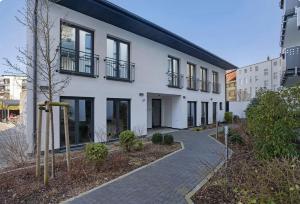 a white building with black windows and a sidewalk at Central Suites in Greifswald