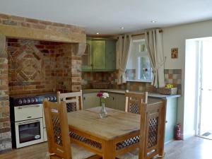 a kitchen with a wooden table and a brick wall at The Old Stables in Bakewell