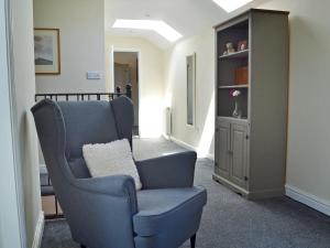 a living room with a chair and a book shelf at The Old Stables in Bakewell +7 photos