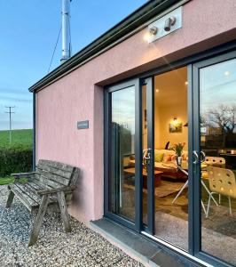 a house with sliding glass doors and a bench at Loom Cottage, Preseli Venture in Haverfordwest